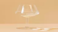 Picture of a small pile of tablets next to a wine glass on a yellow background